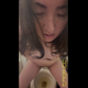 Emi sits on the toilet staring into the camera, spitting and grimacing as she shits diarrhea into the bowl between her legs. Vertical format video. Over 1 minute.